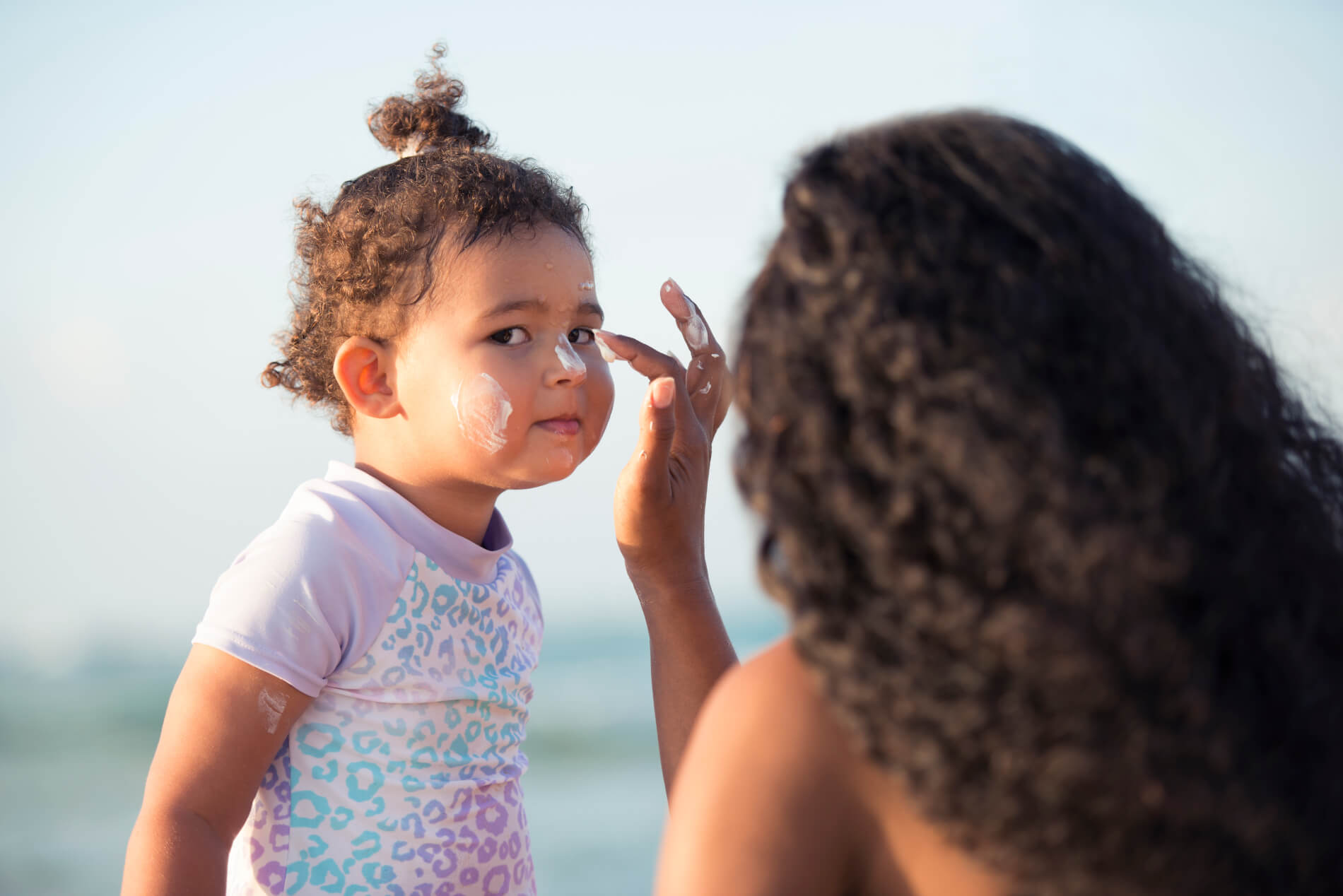 Parent applying sunscreen with UV-filter on child's face